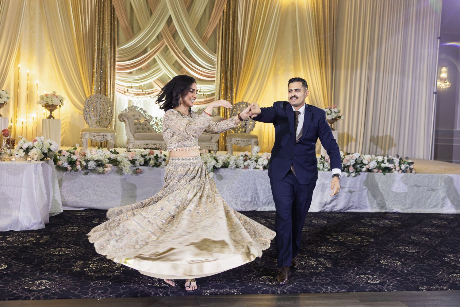 Elegant wedding reception hall decorated with white drapes and golden lighting for a celebration.