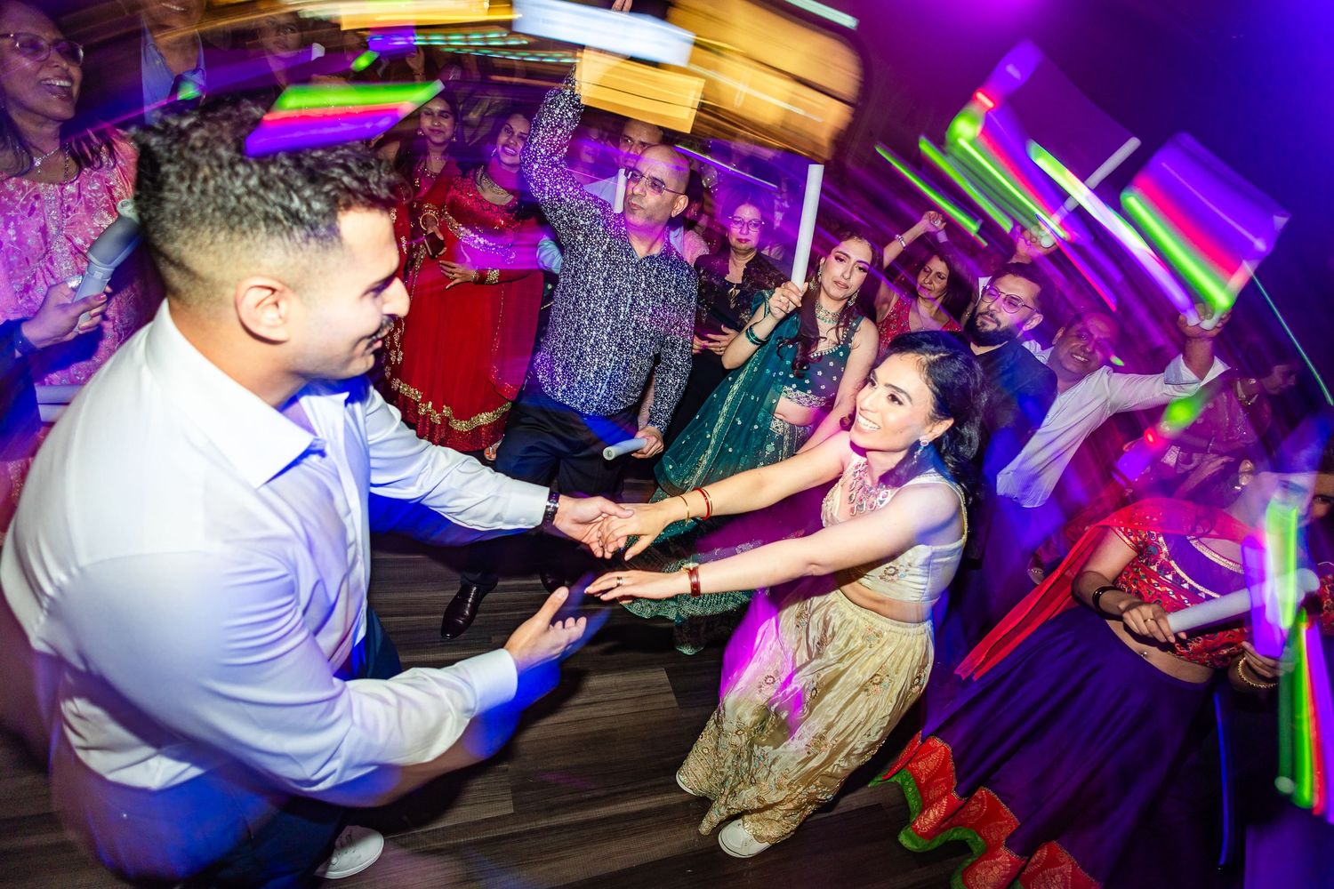 People dancing and socializing at a nightclub with vibrant purple lighting and energetic atmosphere.
