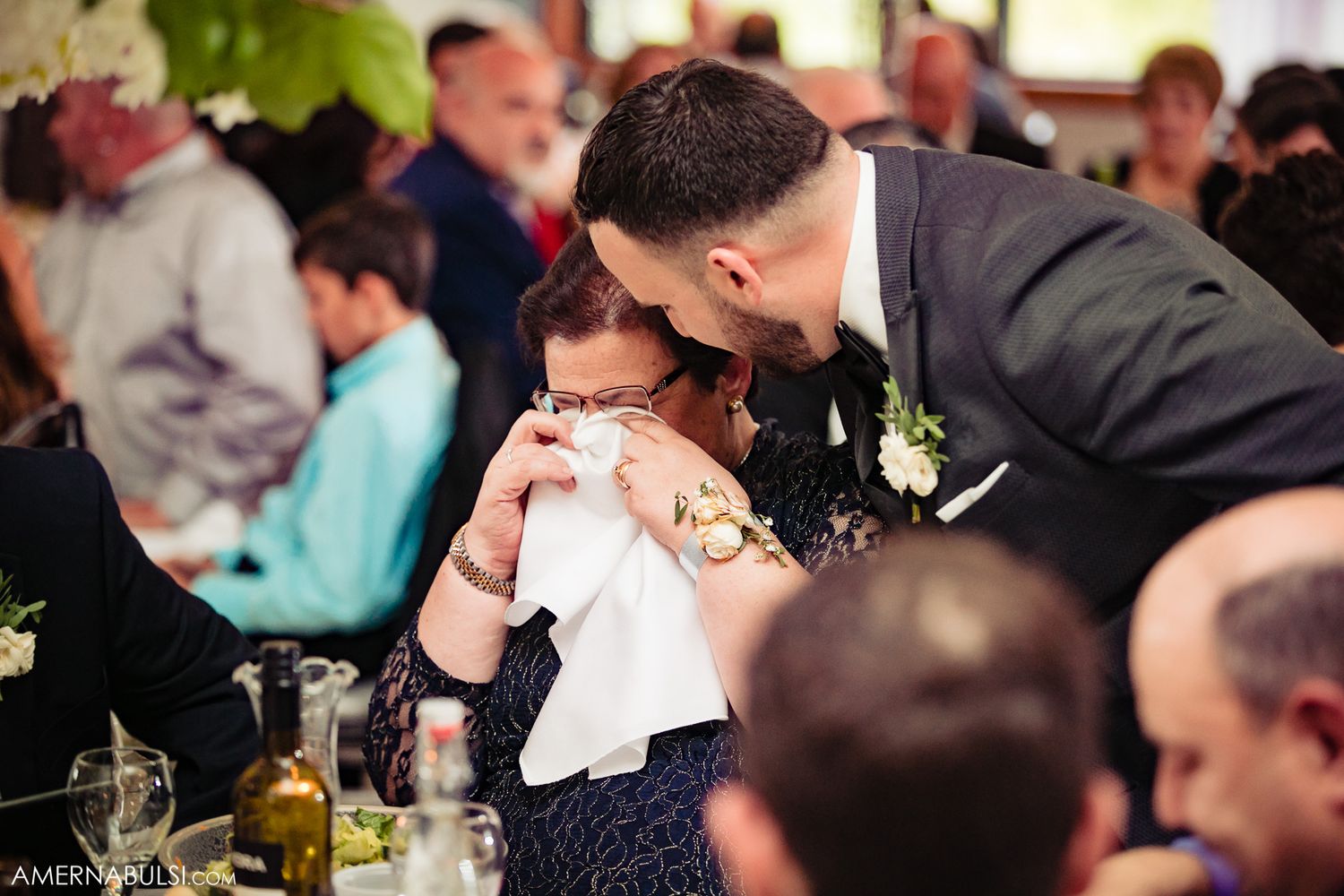 Wedding guests enjoying a lively reception celebration with drinks and laughter.