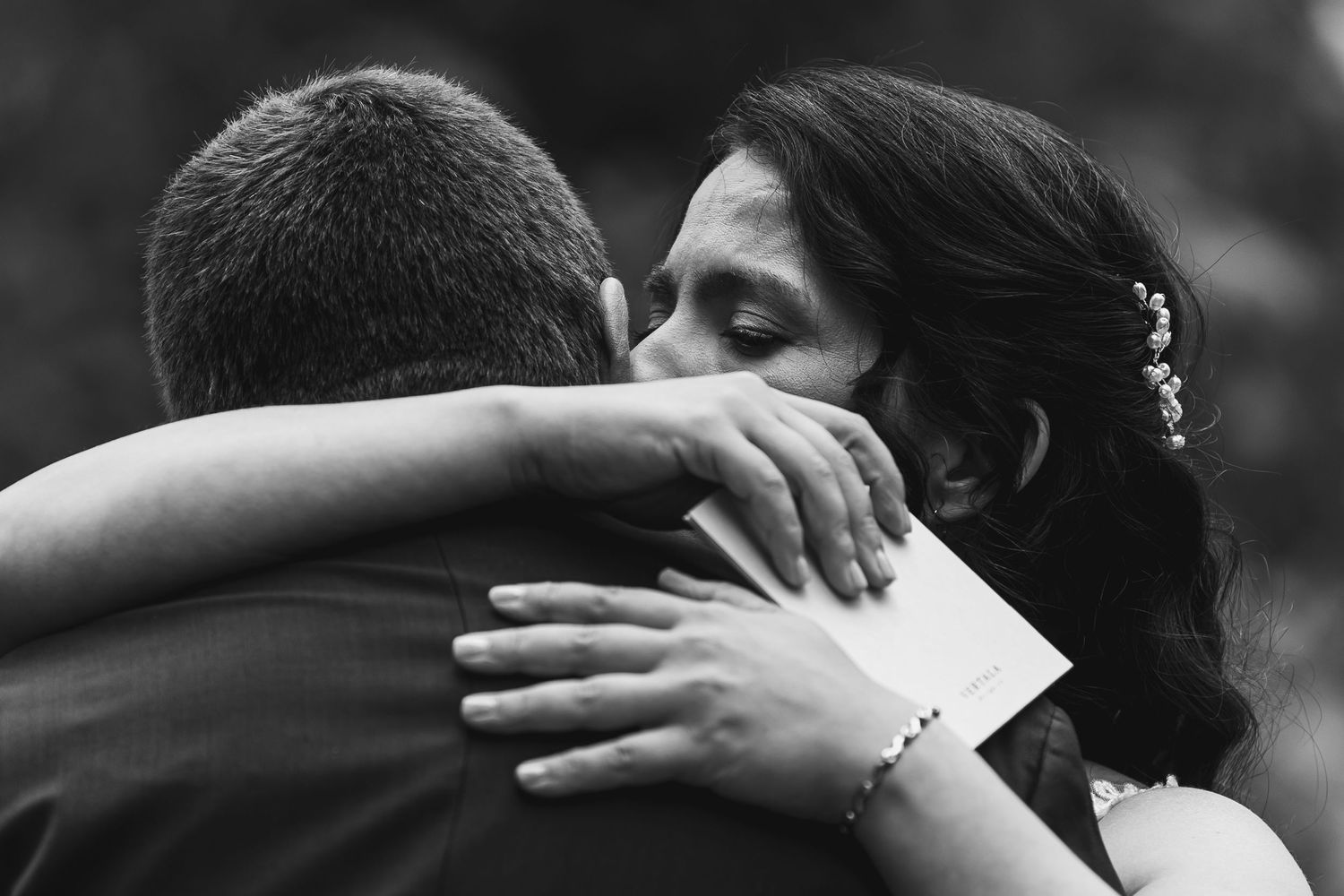 Black and white photo of a bride and groom sharing an emotional embrace on their wedding day.