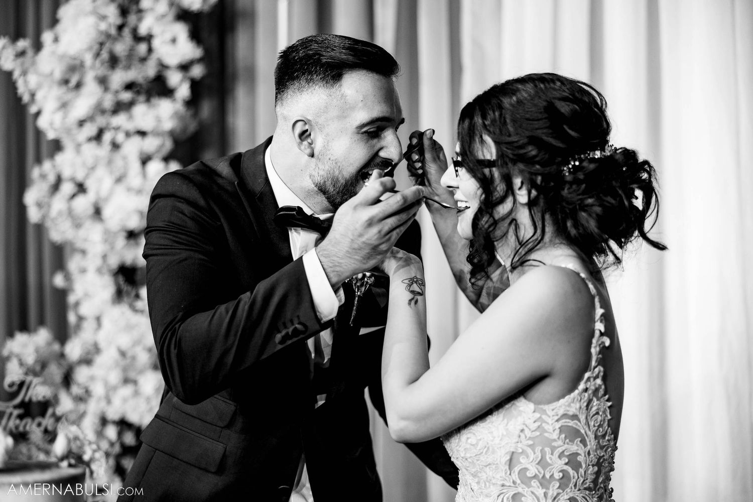 A romantic black and white photo of a couple sharing an intimate moment at their wedding reception.