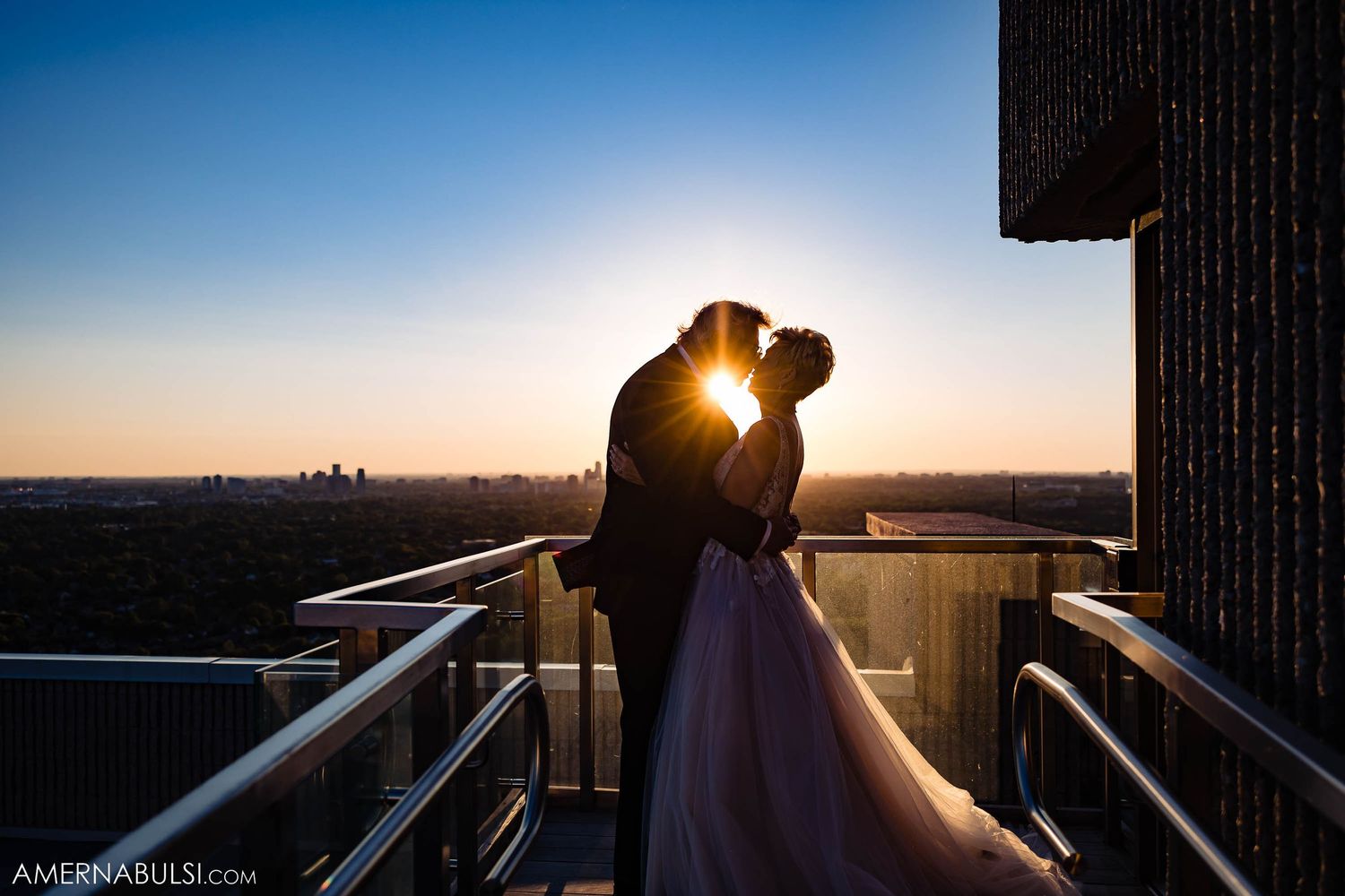 Silhouetted newlyweds share an intimate moment at sunset on a city rooftop.