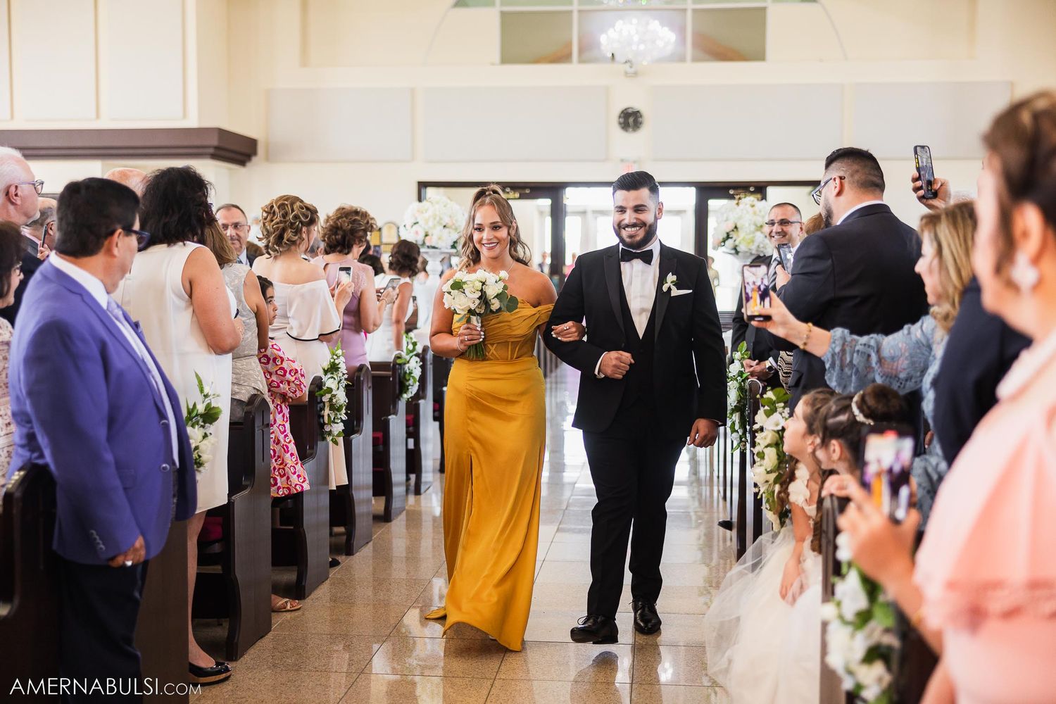 Wedding party members walk down the aisle during ceremony procession.