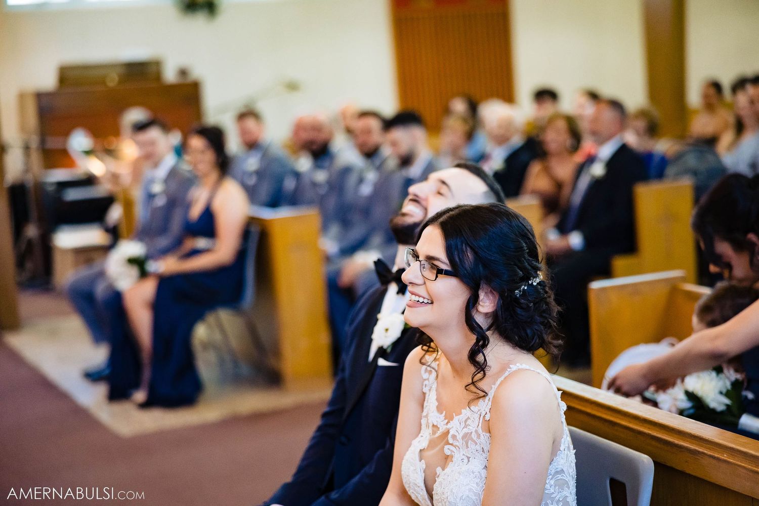 Wedding attendees seated in church pews during ceremony.