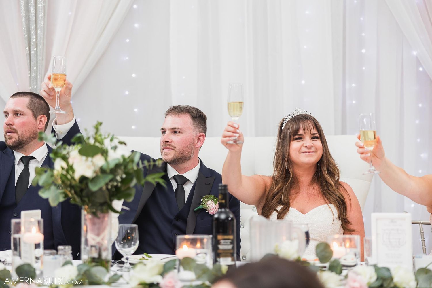 Newlyweds and guests raise glasses in celebratory toast at reception.