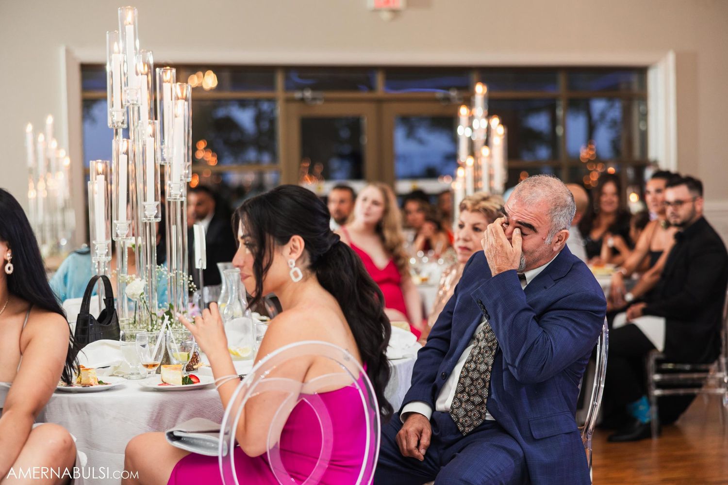 Guests seated at elegant reception tables with tall crystal candelabras and formal place settings.