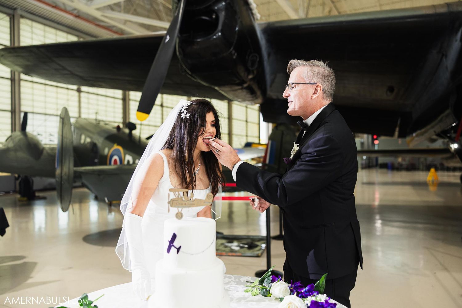 Wedding ceremony in aviation museum with couple sharing champagne toast.