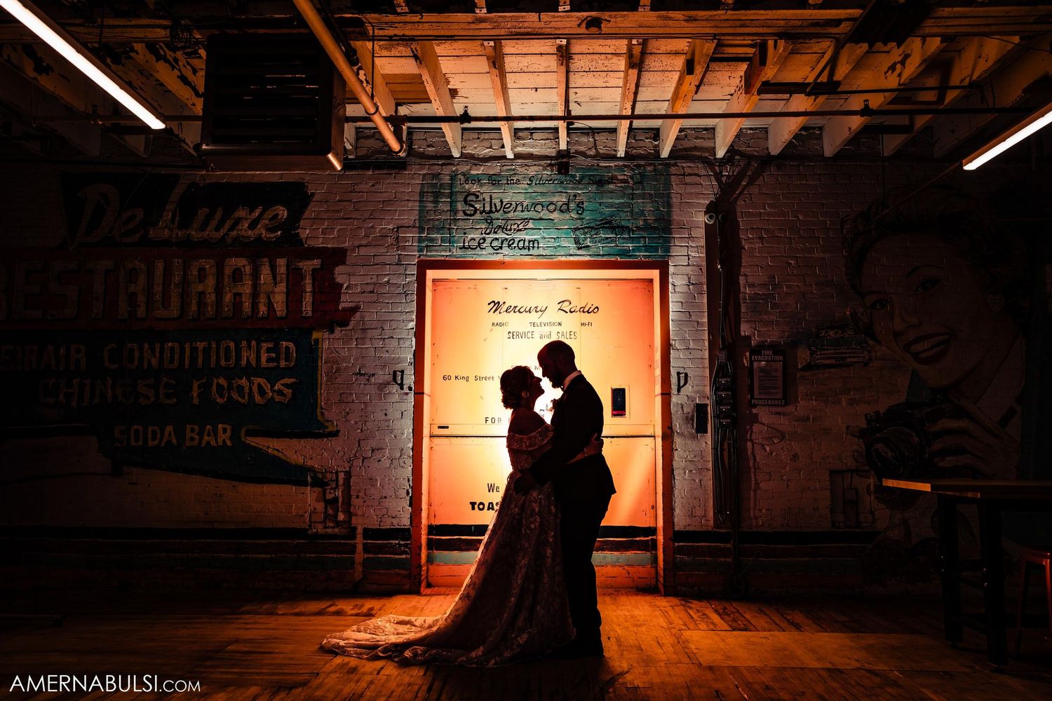 Silhouetted couple shares intimate moment in front of backlit doorway.
