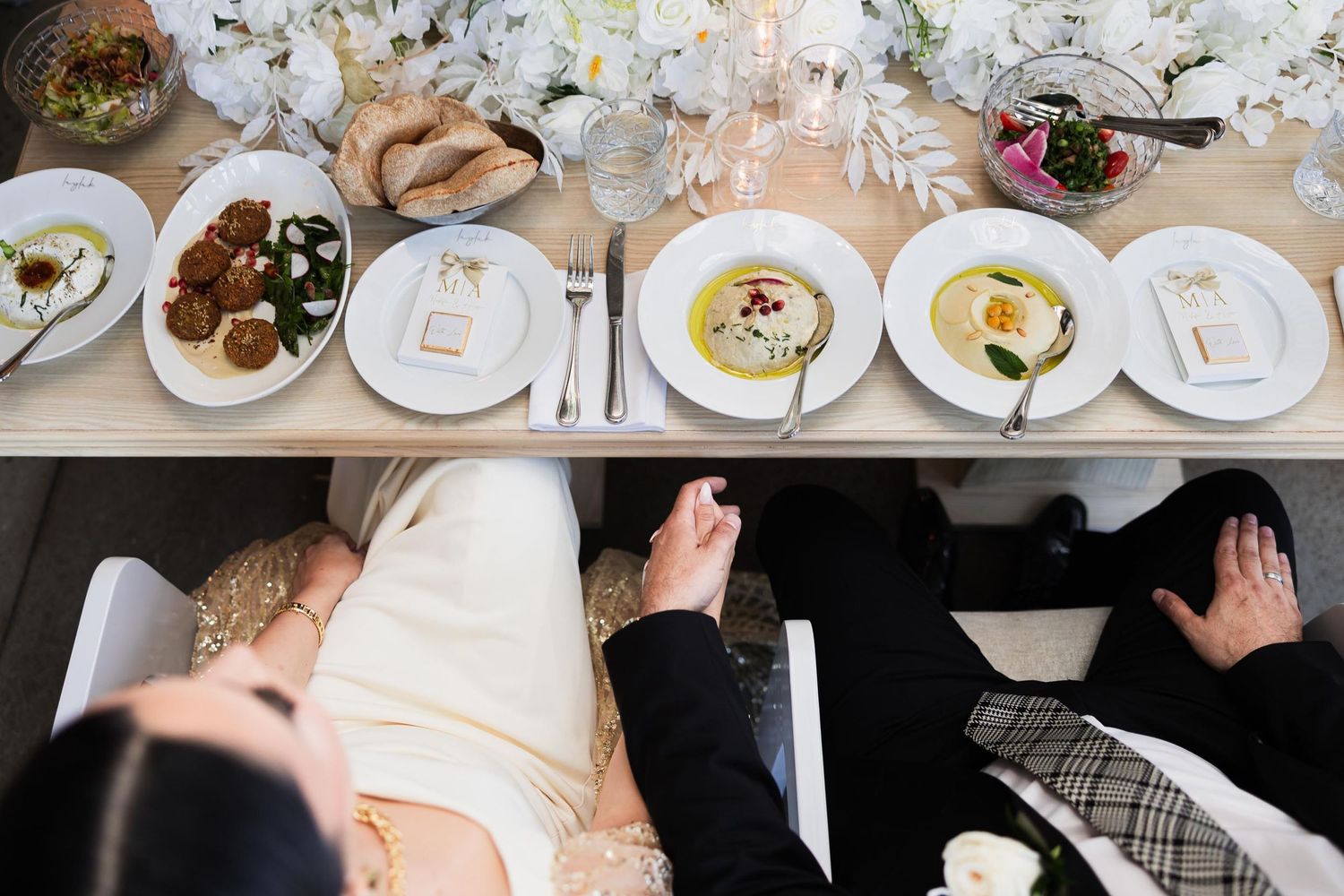 Elegant table setting at a wedding reception with white plates and decorative elements.