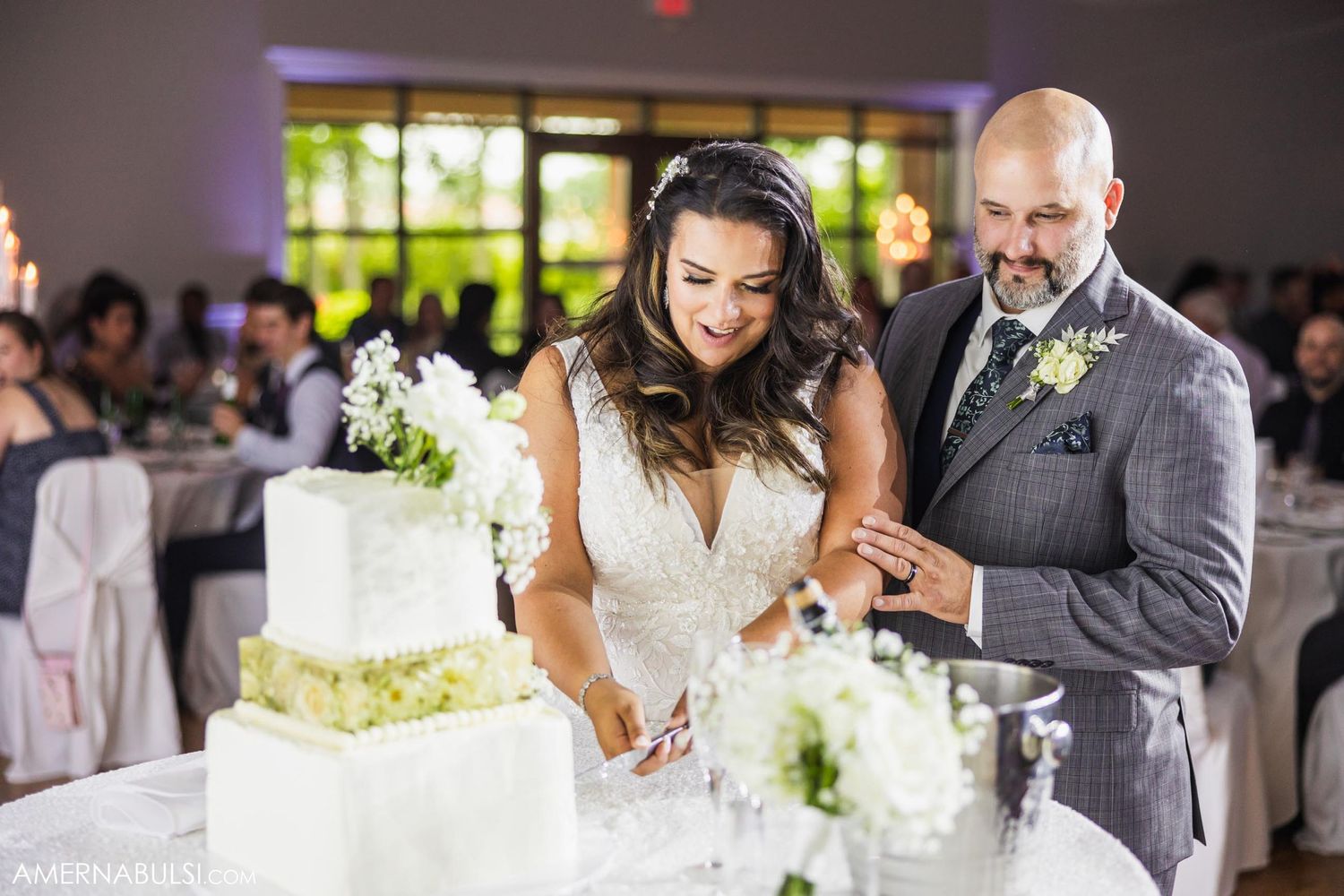 A couple cutting their white wedding cake together at their reception.