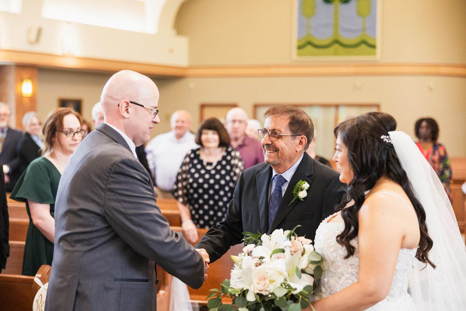 Wedding ceremony gathering in a church with floral decorations and guests.