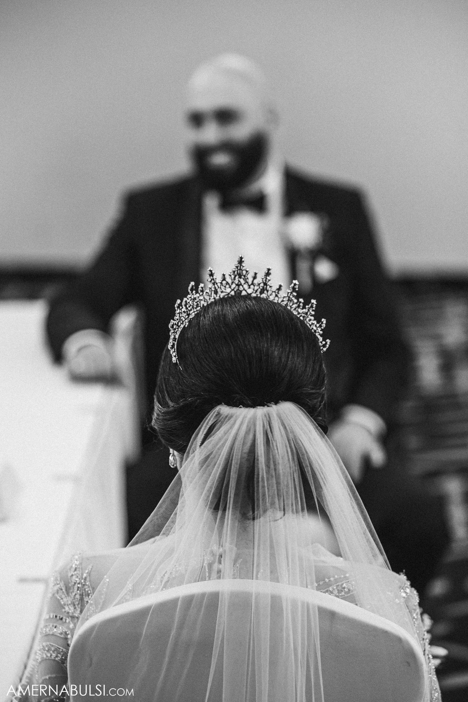 Close-up of a delicate crystal tiara and veil against a black and white background.