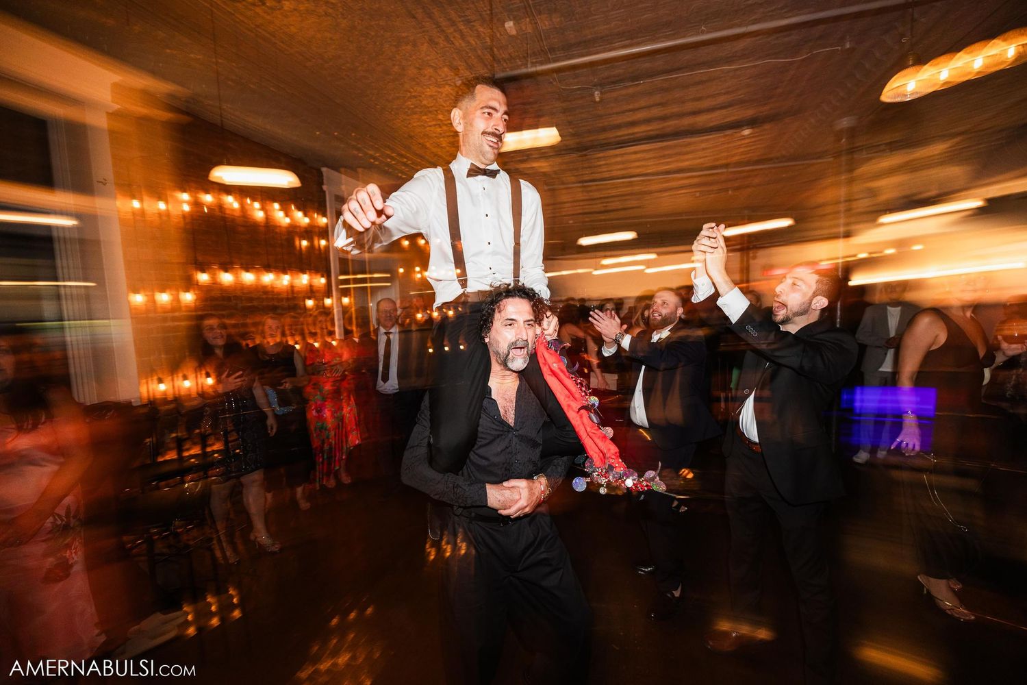 Energetic dance party scene with motion blur at wedding reception.