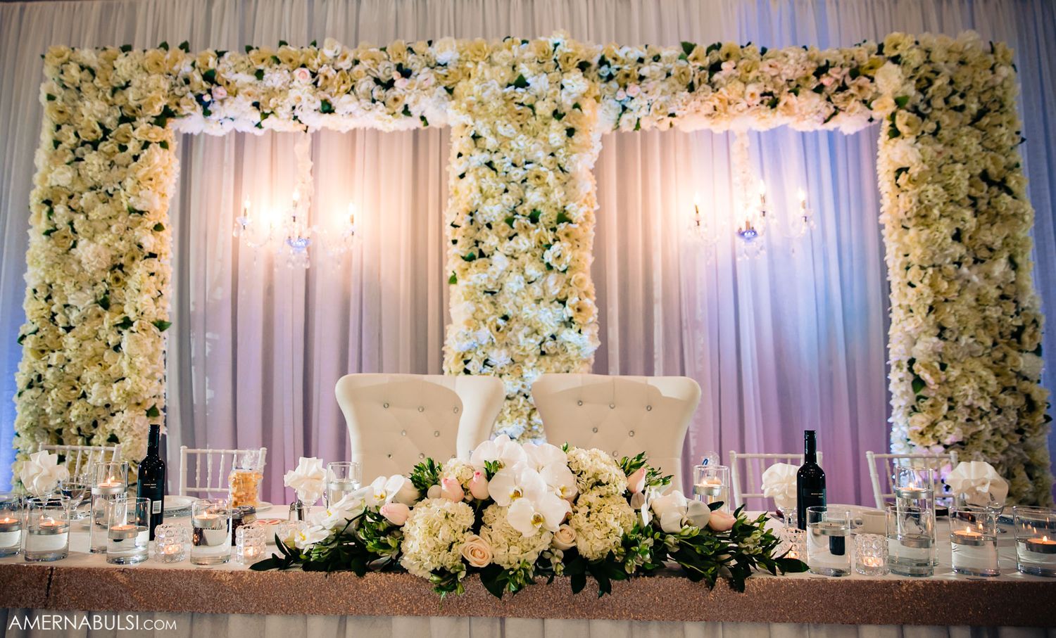 Elegant wedding reception backdrop with white floral arrangements and soft lighting creating a romantic atmosphere.