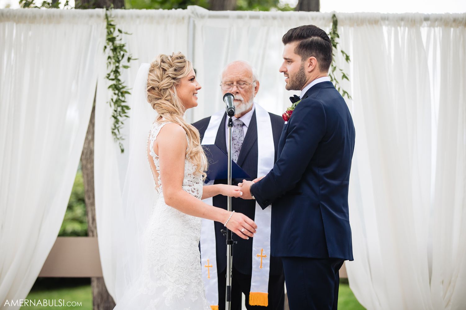 Emotional first look moment between couple at outdoor wedding ceremony with white draping and greenery.