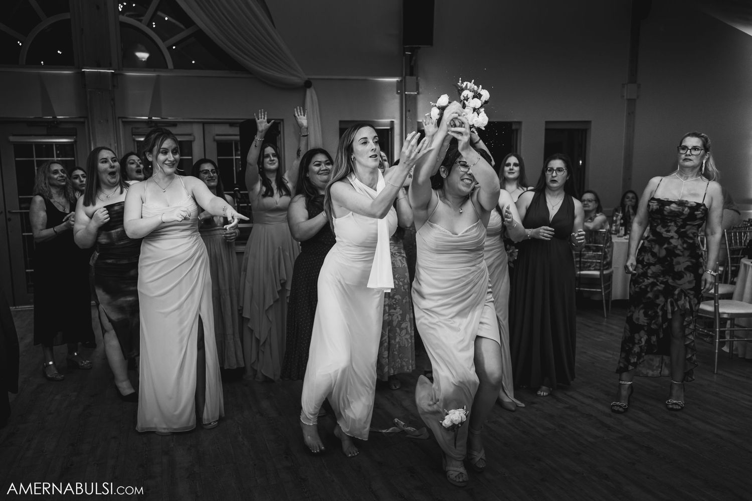 Wedding guests dance together in elegant attire during an indoor reception celebration.