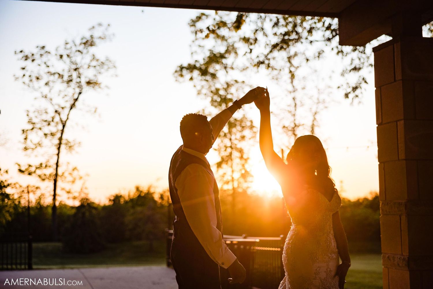 Couple dancing in silhouette against a stunning sunset backdrop with trees.