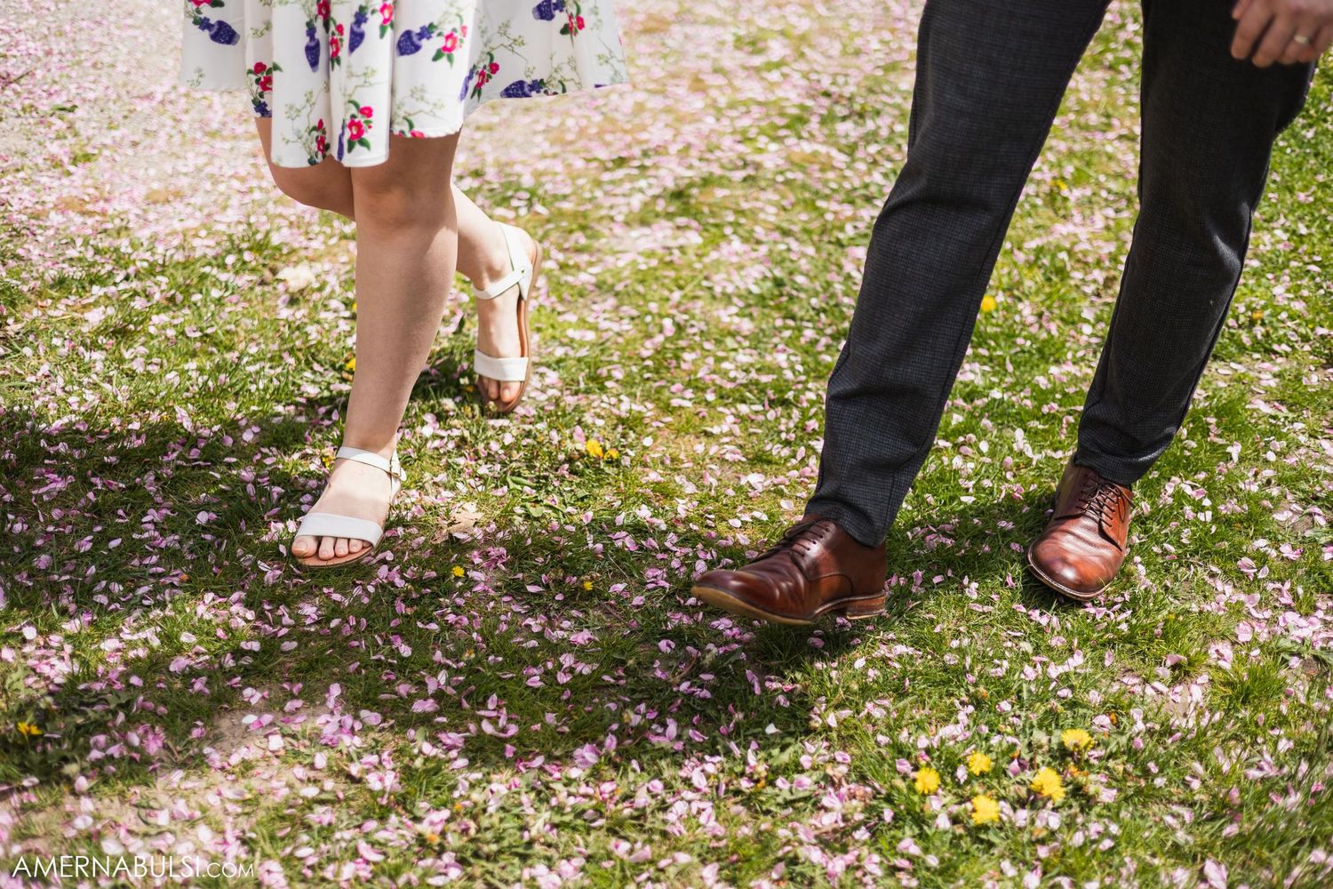 Close-up of couples' feet and legs while walking on a petal-covered path.