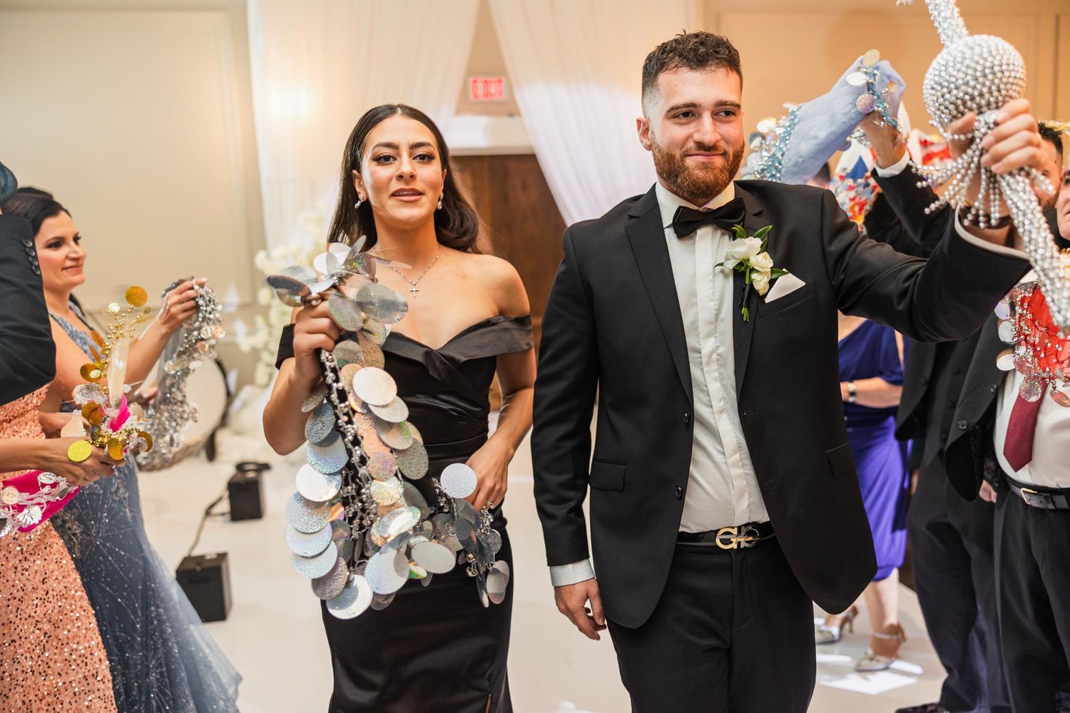 Wedding party celebrates in a decorated hallway with silver streamers and party accessories.