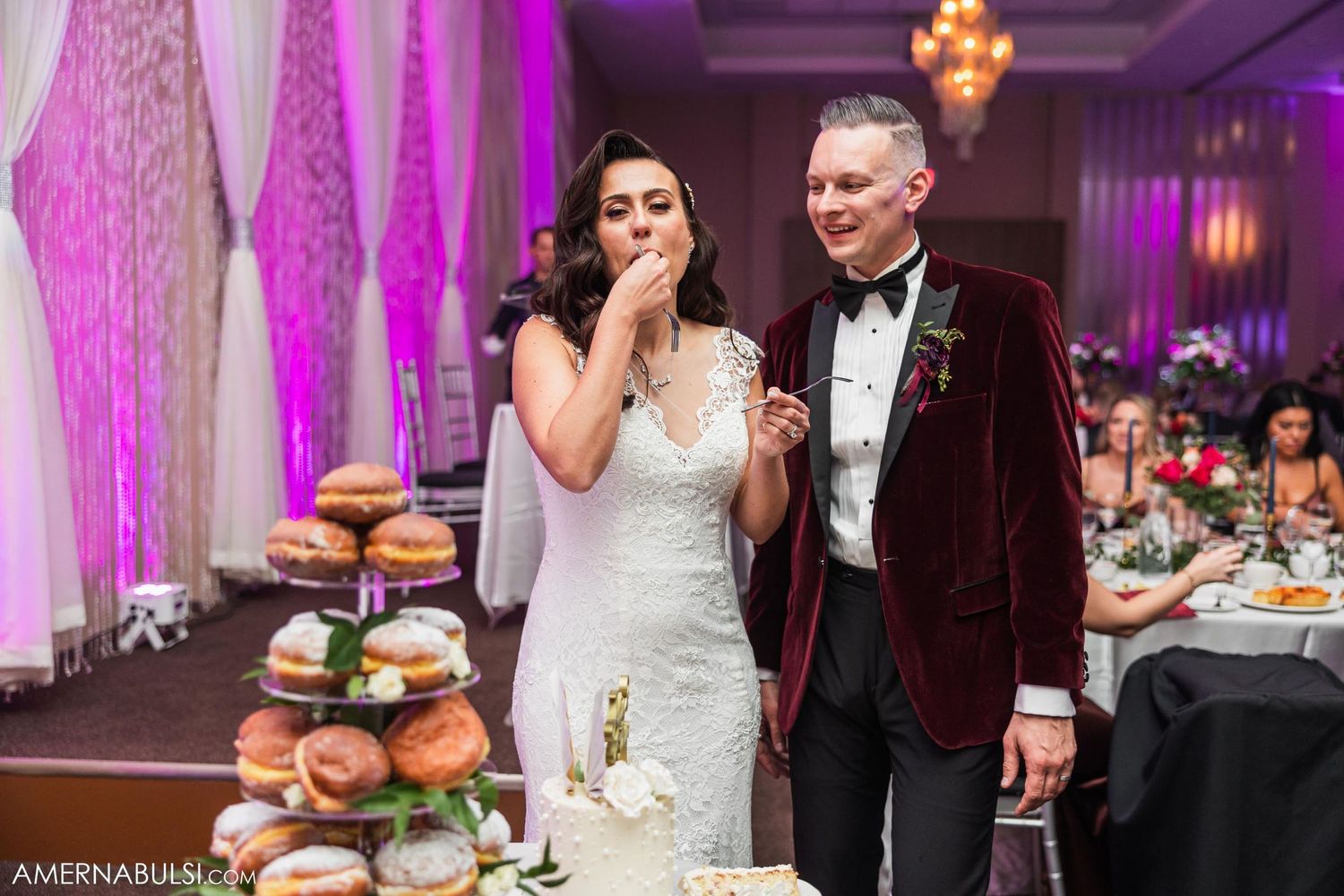 Wedding couple enjoying a moment at their dessert table with pink backdrop.