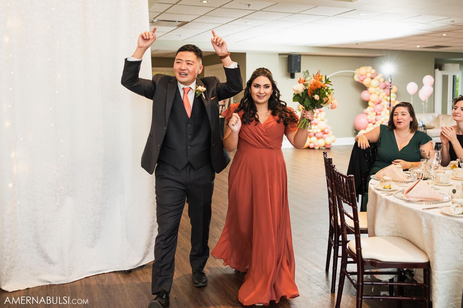 Wedding party members celebrate with raised arms during reception entrance.