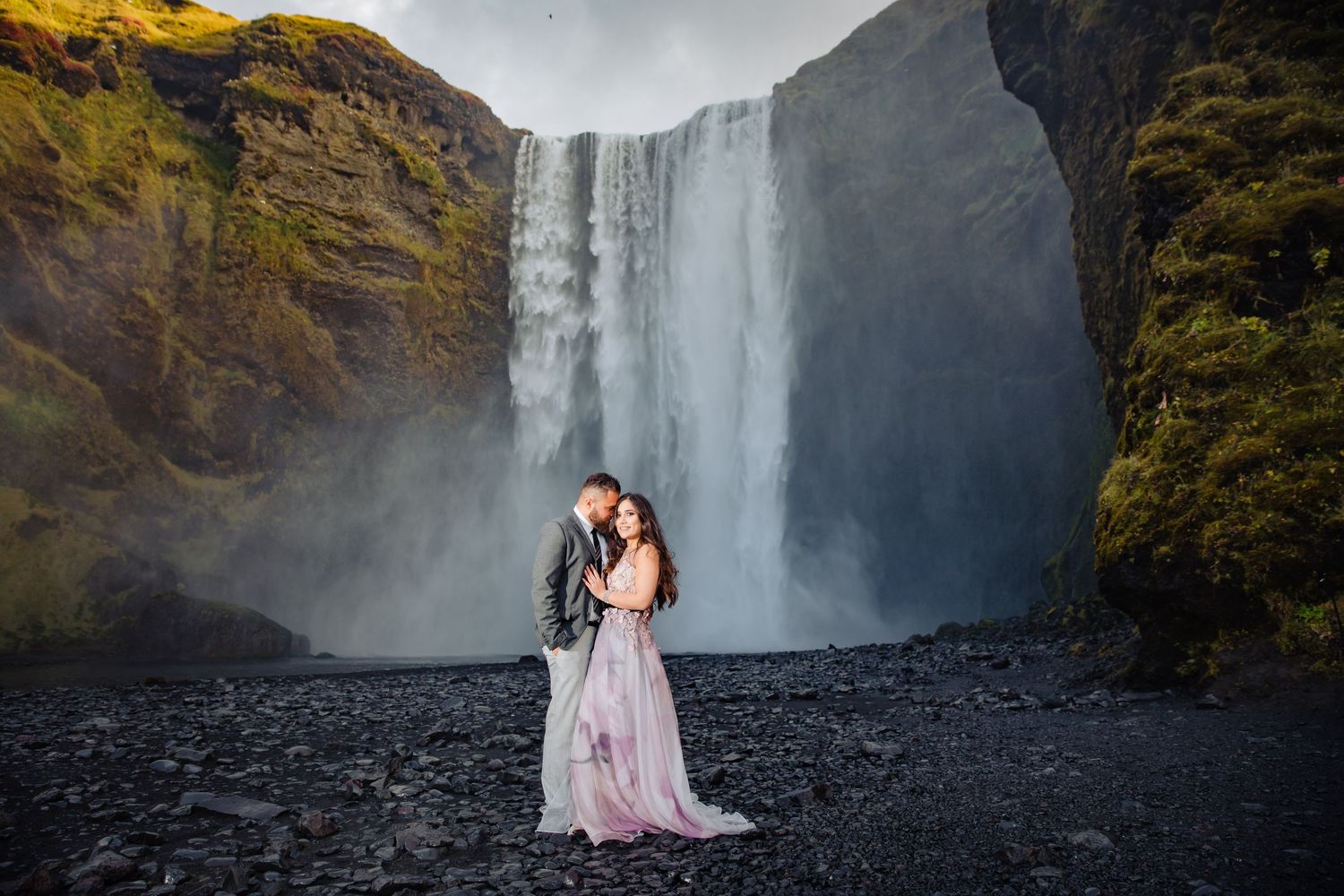 Dramatic waterfall cascades down black rocky cliffs in Iceland during moody overcast weather.