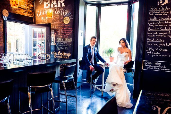 Wedding celebration inside rustic bar with chalkboard walls and warm lighting.