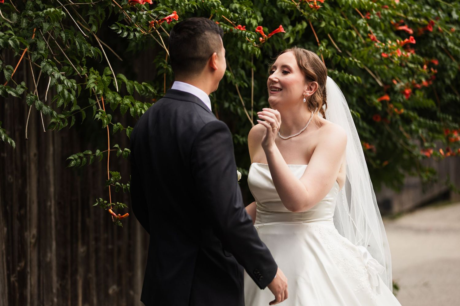 Bride laughing joyfully with groom during romantic outdoor wedding portrait session near floral vines.