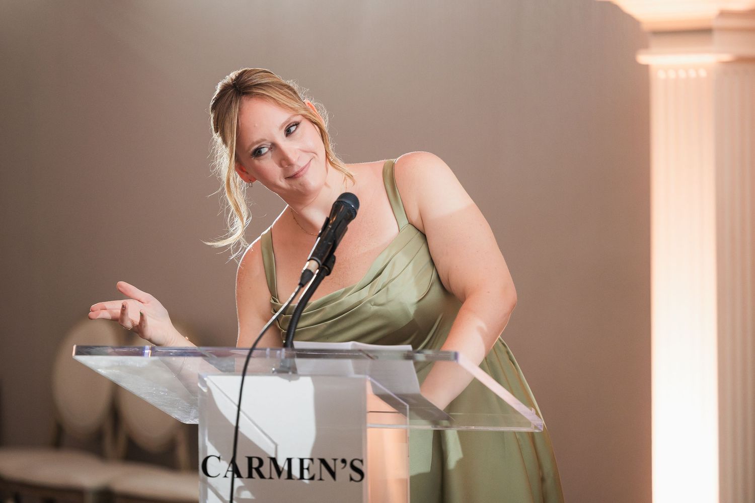 Woman in green dress speaking at Carmen's podium.