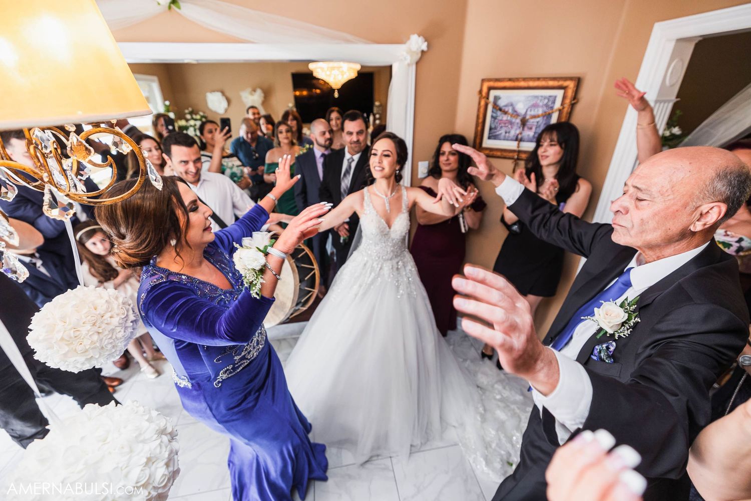 Energetic wedding celebration with guests dancing and clapping in a decorated indoor space.