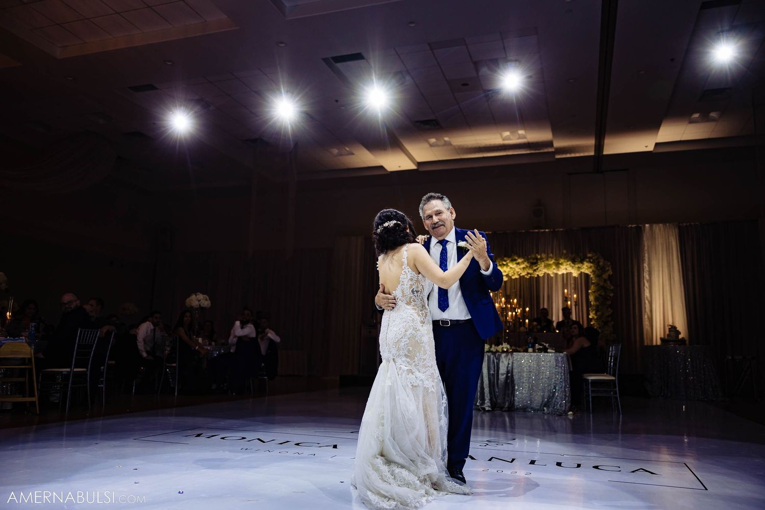A couple dances together under dramatic spotlights during their wedding reception.