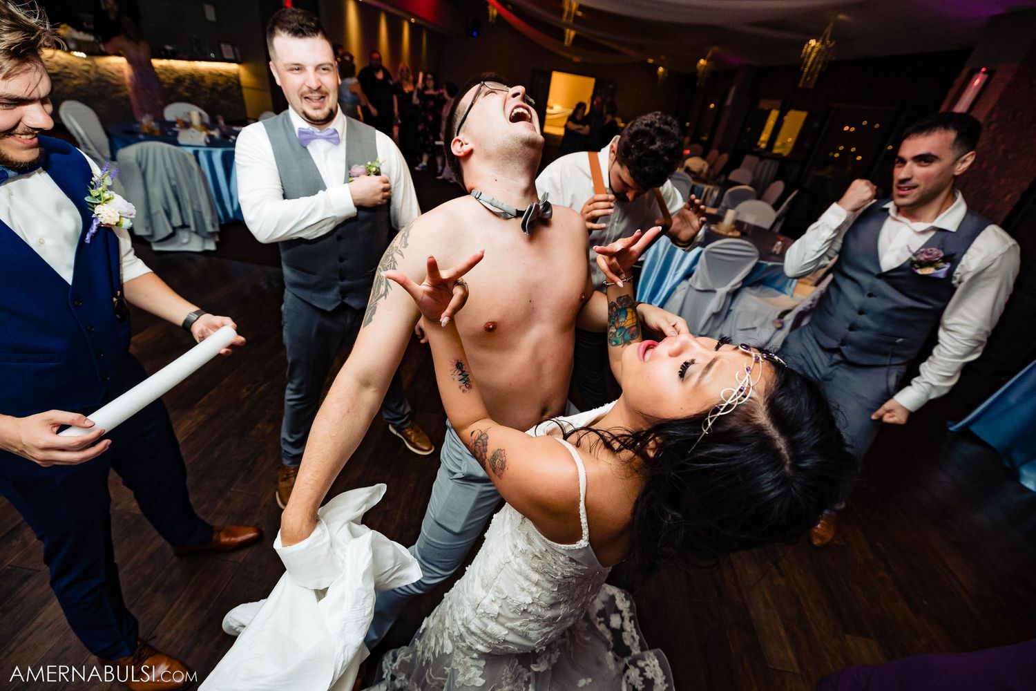 Wedding reception dance party with guests in formal attire dancing enthusiastically on wooden floor.