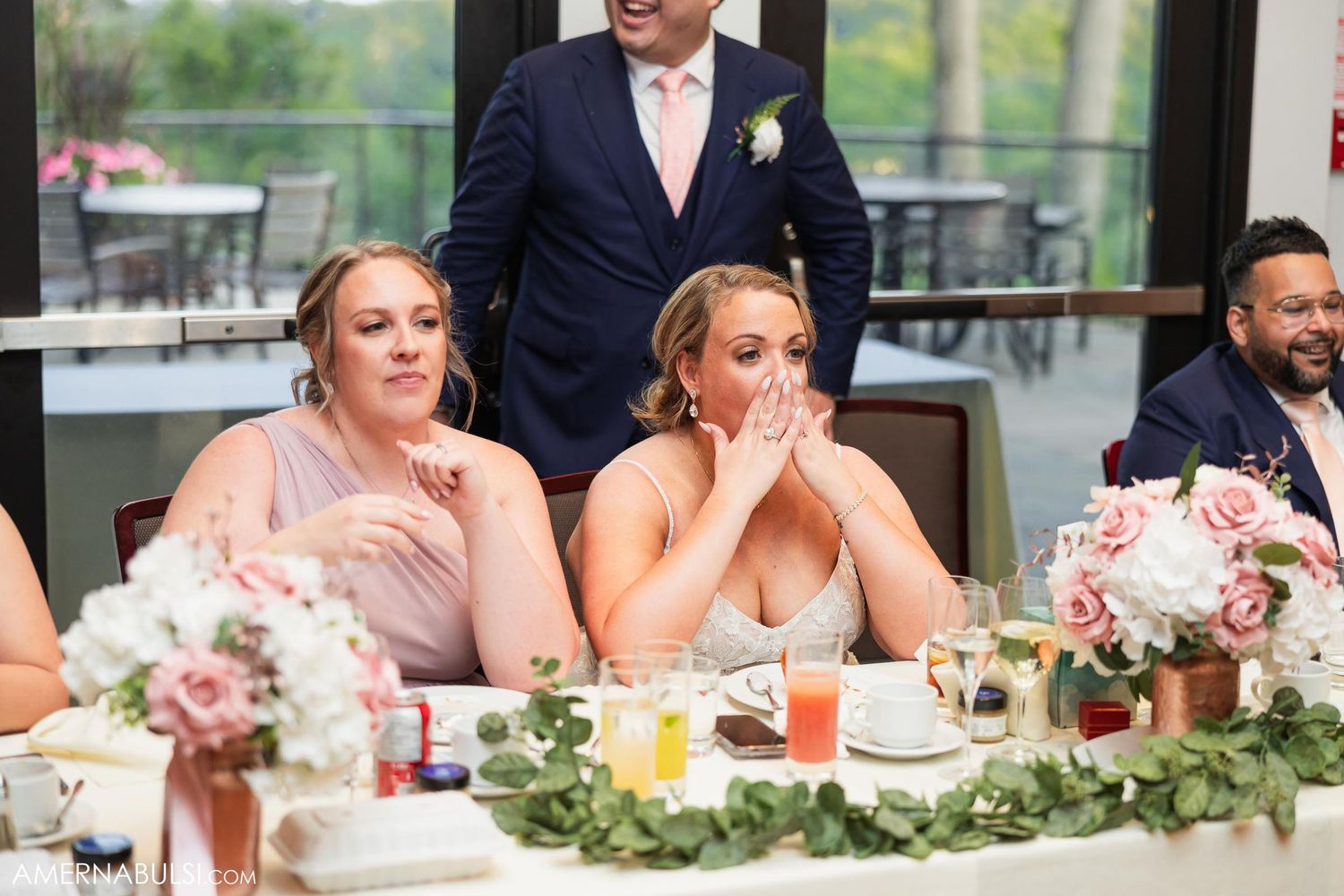 Wedding party members react emotionally at reception head table.