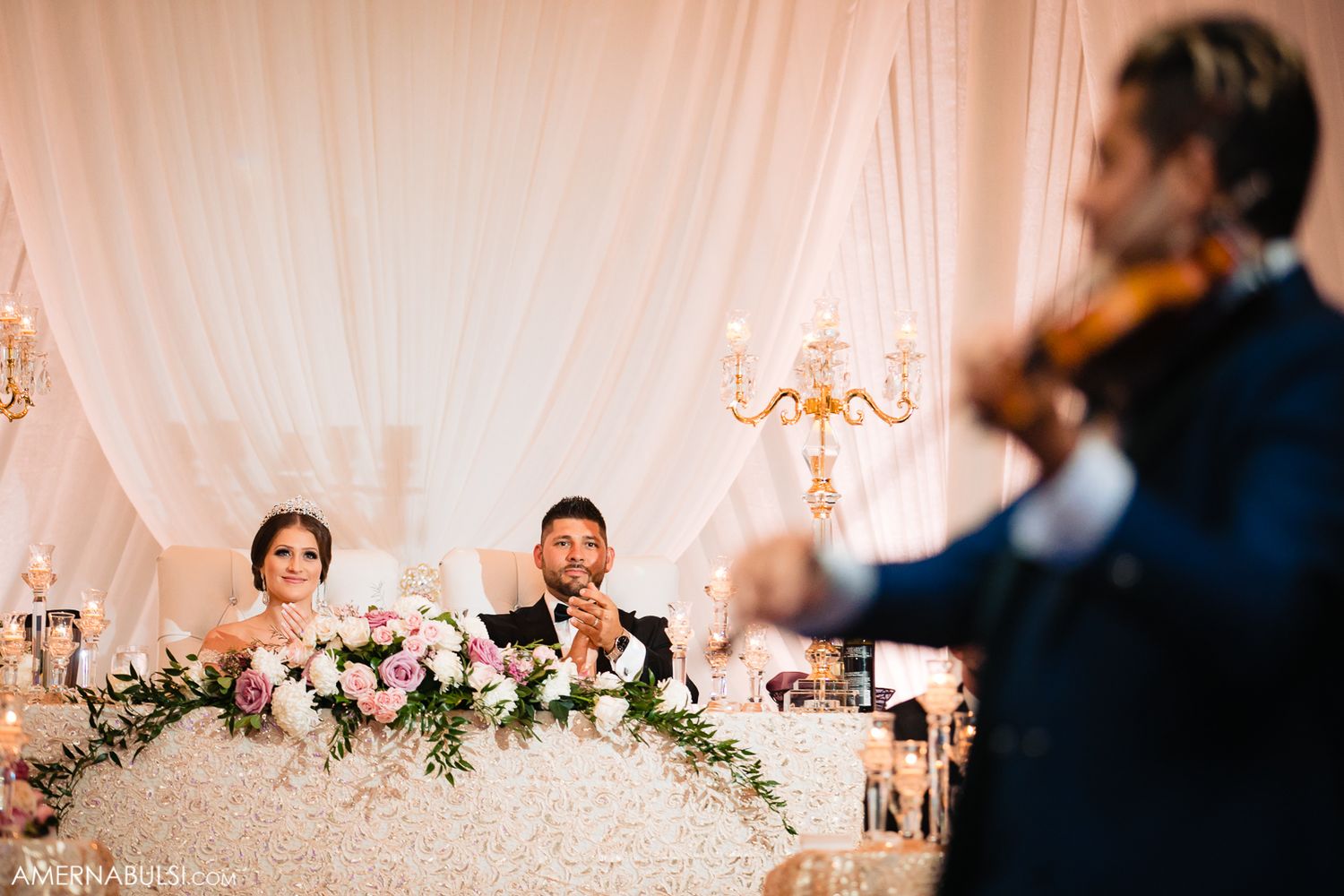 Elegant wedding reception setup with white draping, floral arrangements, and romantic lighting.