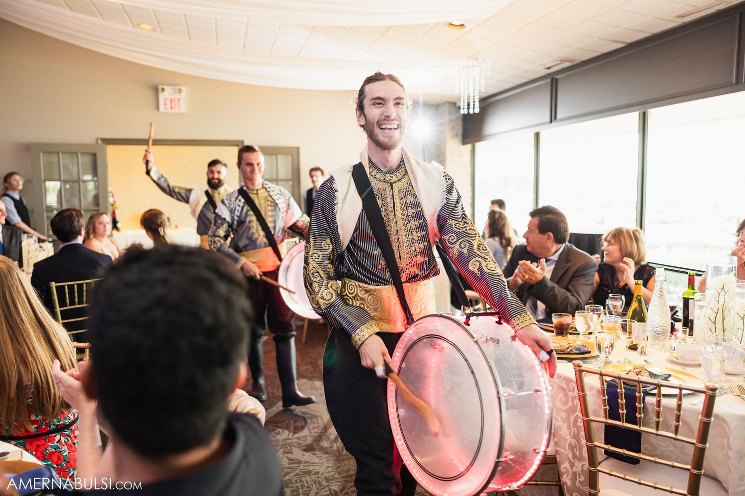 Drummer performs standing on chair during festive wedding reception.