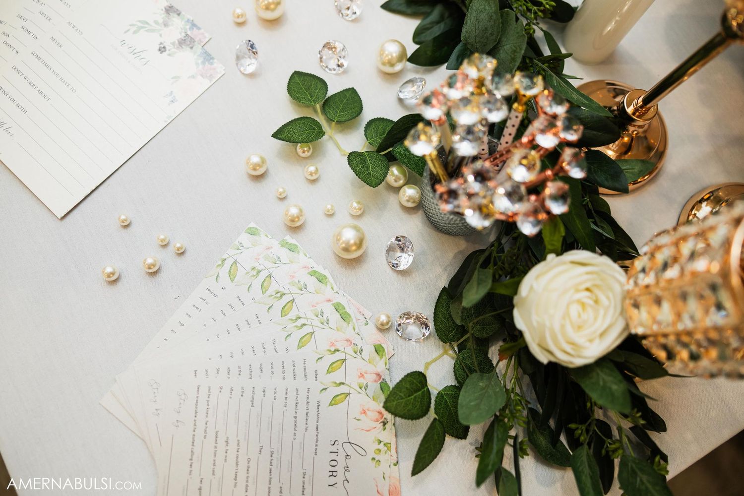 Wedding stationery with scattered pearls and white rose floral decorations.