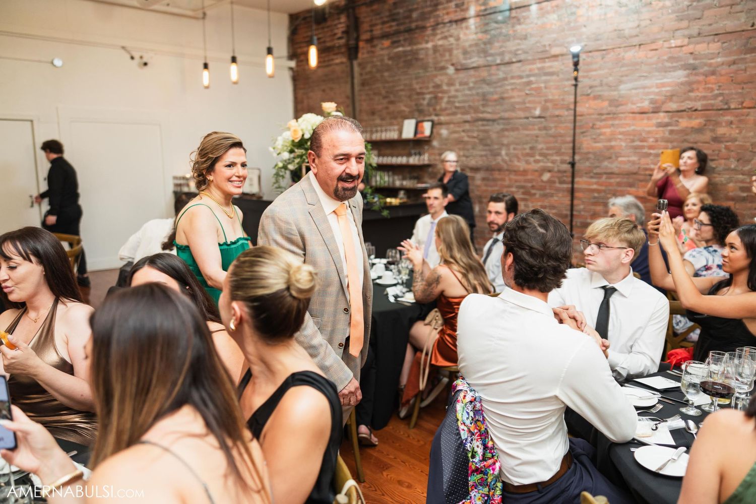 Wedding guests enjoying a lively reception in an industrial-style venue with exposed brick walls.