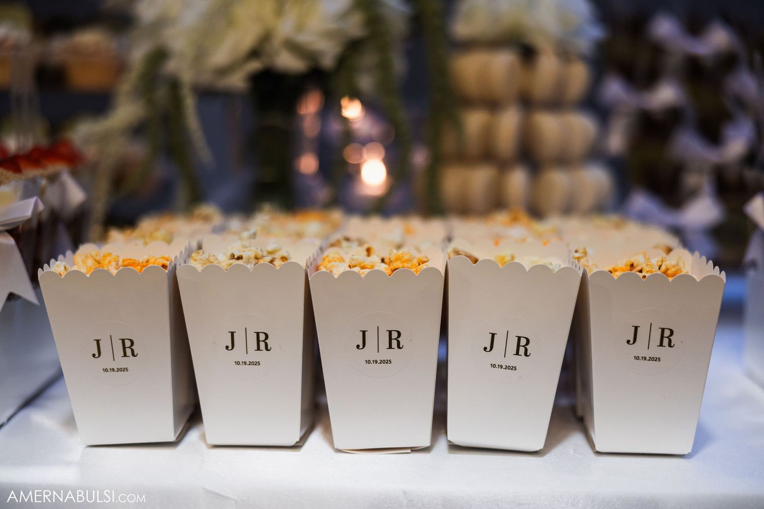 Row of labeled place cards arranged neatly on white linen for wedding reception seating.