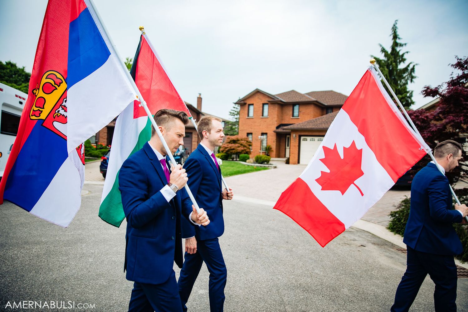 Wedding guests wave Canadian and Serbian flags during outdoor celebration.