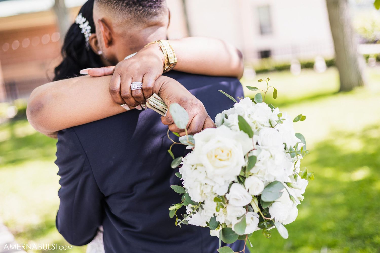 Close-up of an embrace with white bridal bouquet visible against a navy suit.