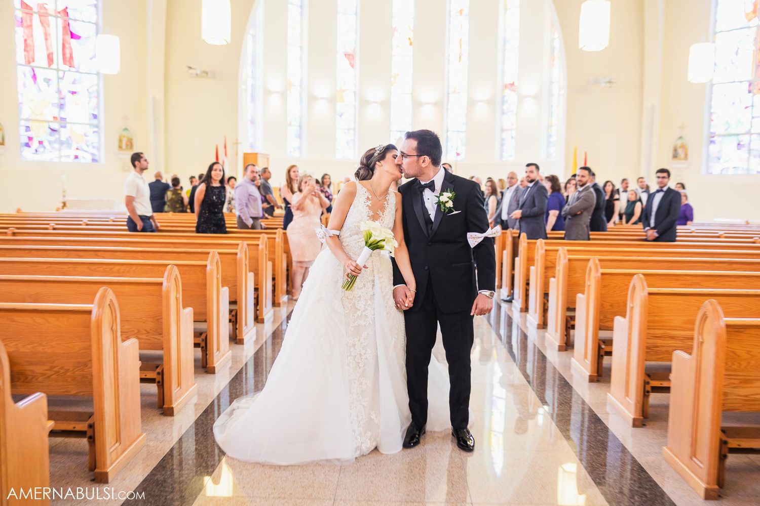 Joyful newlyweds walking down church aisle while guests celebrate from the pews.