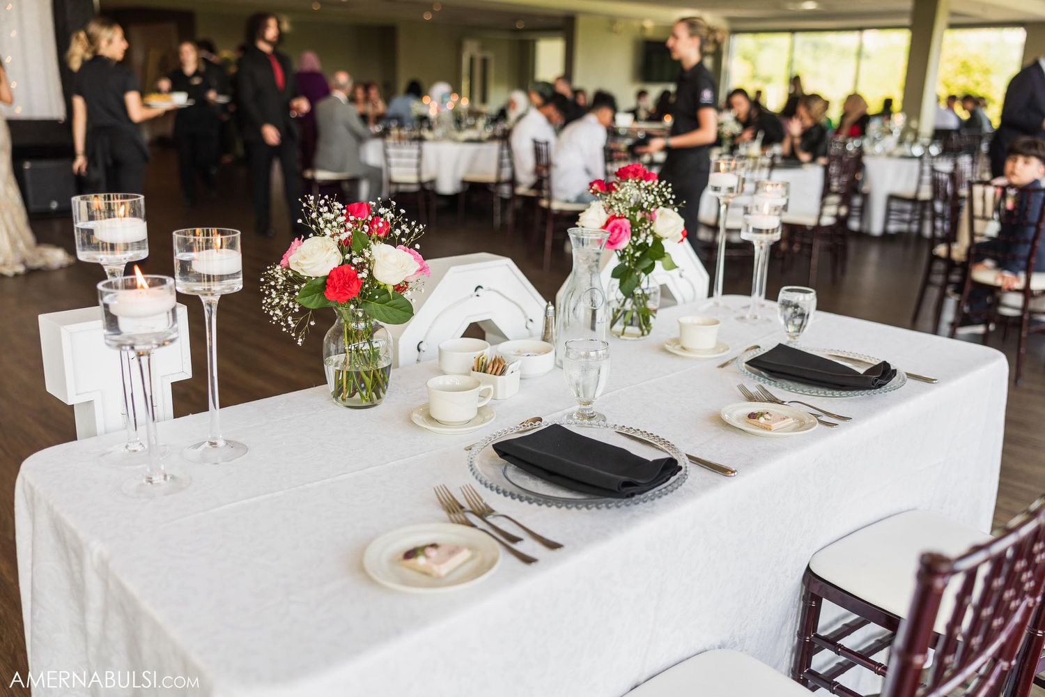 Elegant wedding reception table setting with floral centerpieces and white linens.