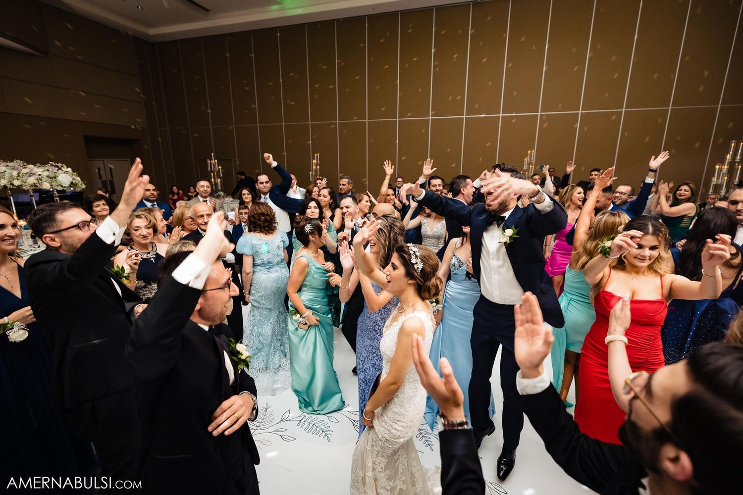 Wedding guests dancing and jumping with joy at reception celebration.