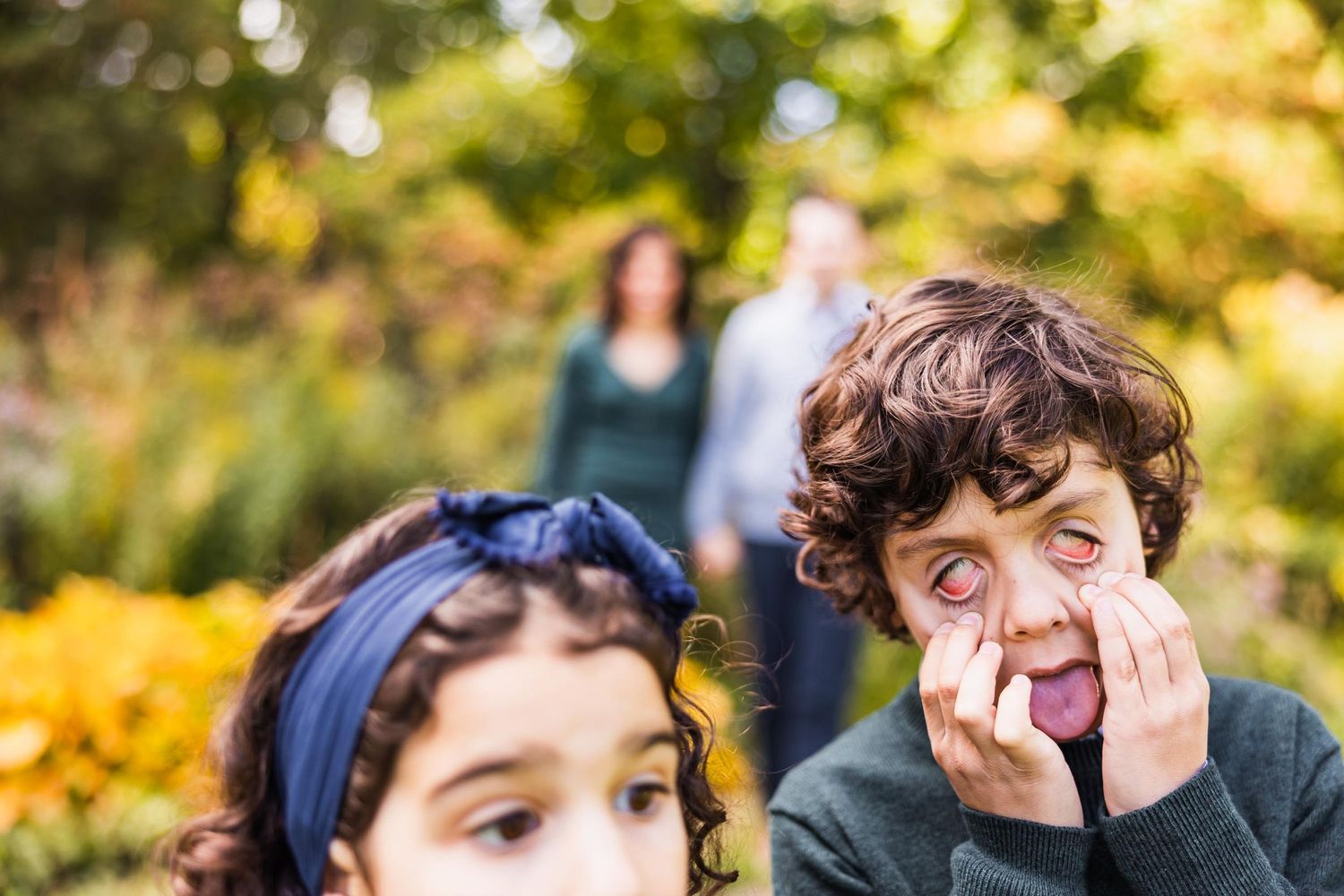 Children making playful expressions in a sunlit autumn garden.