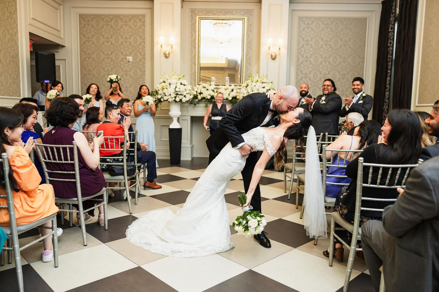 Wedding ceremony celebration in an elegant ballroom with guests seated in chiavari chairs.