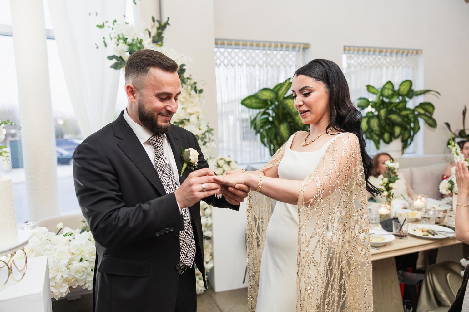 An intimate moment during a ring exchange ceremony with gold and white decor.
