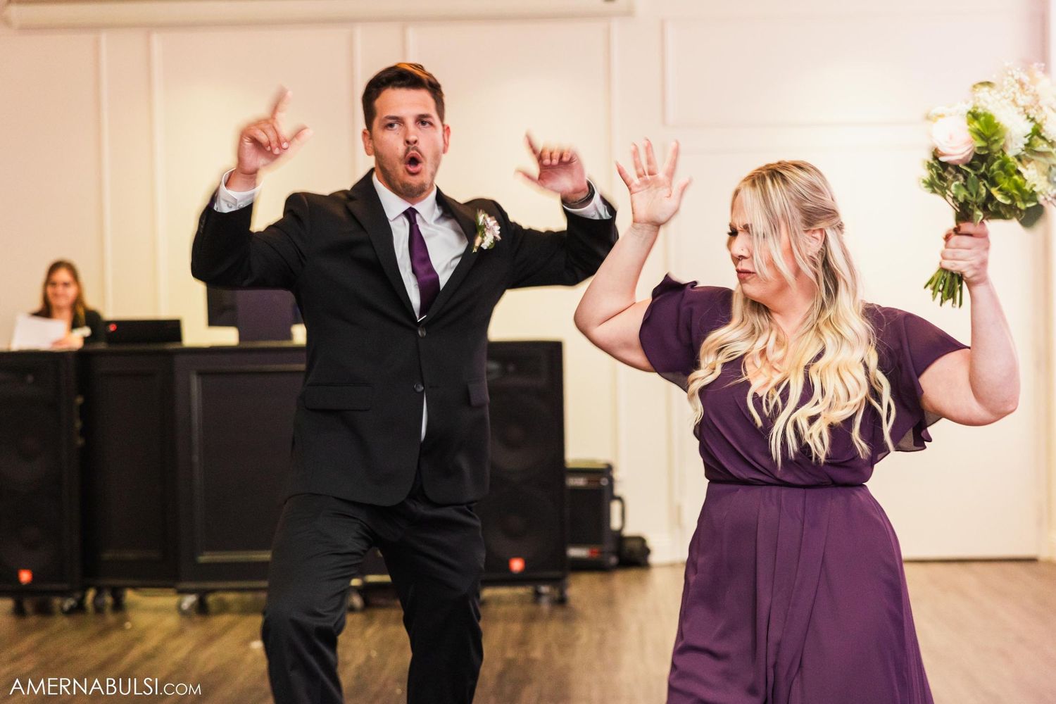 Wedding party members dancing energetically in formal attire at reception.