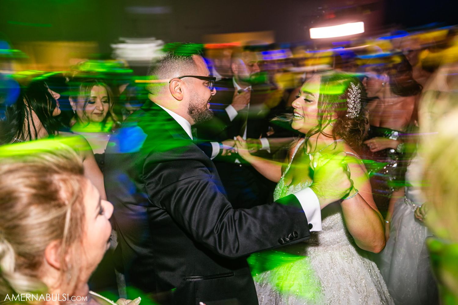 Lively wedding reception dance floor with colorful green lighting effects.