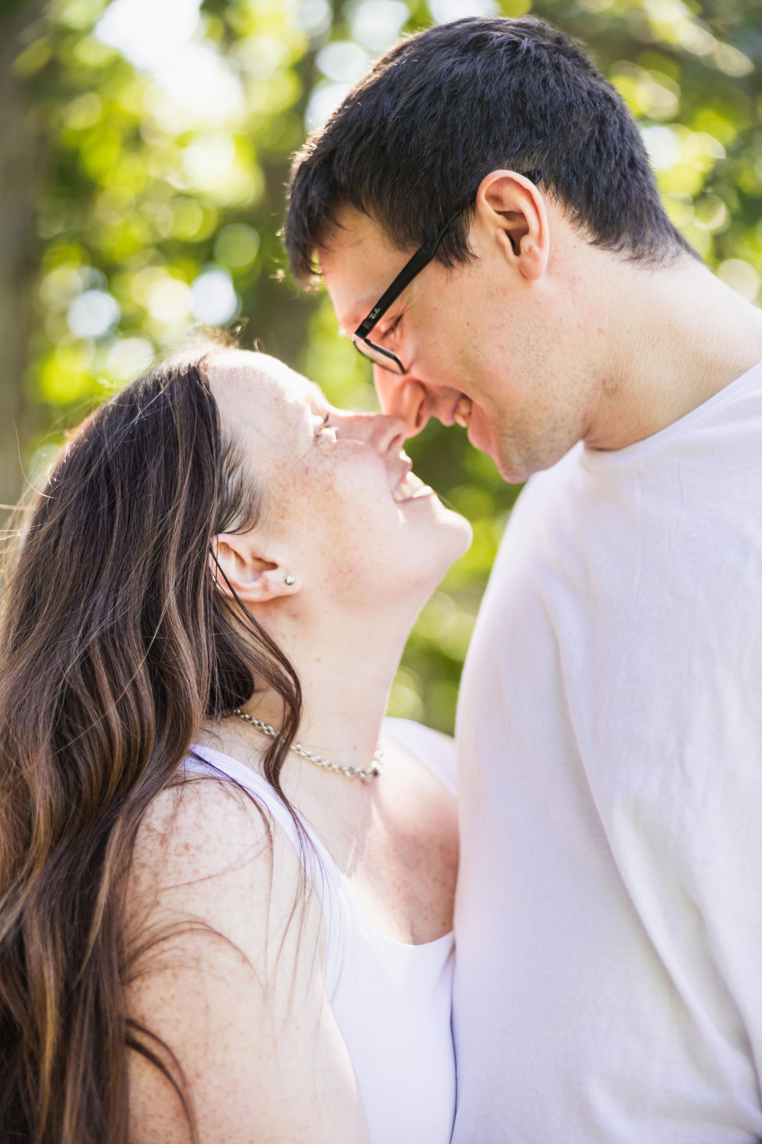 Intimate couple moment photographed in soft natural lighting with bokeh background.