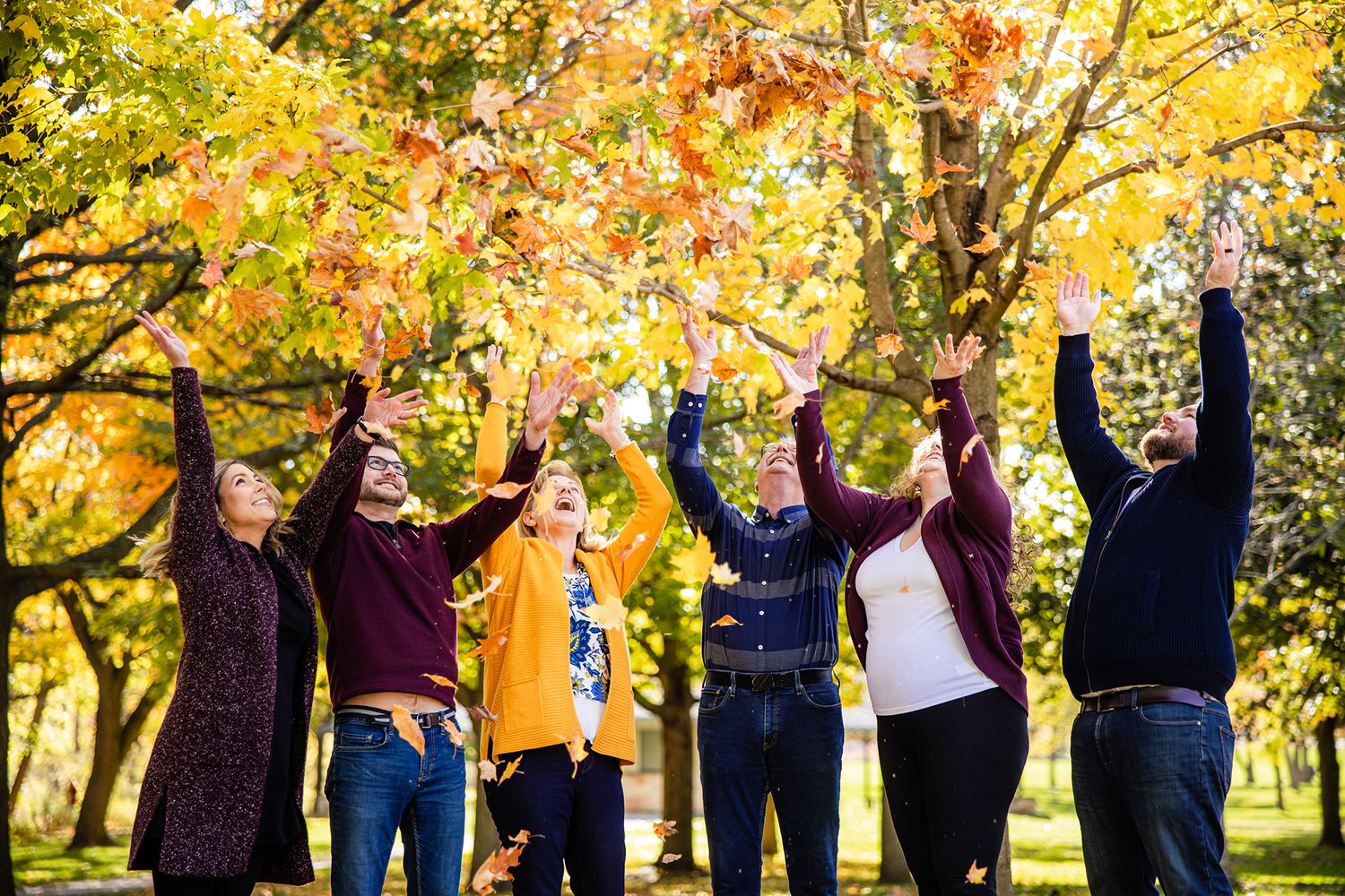 Group photo series with people tossing autumn leaves in a park setting.
